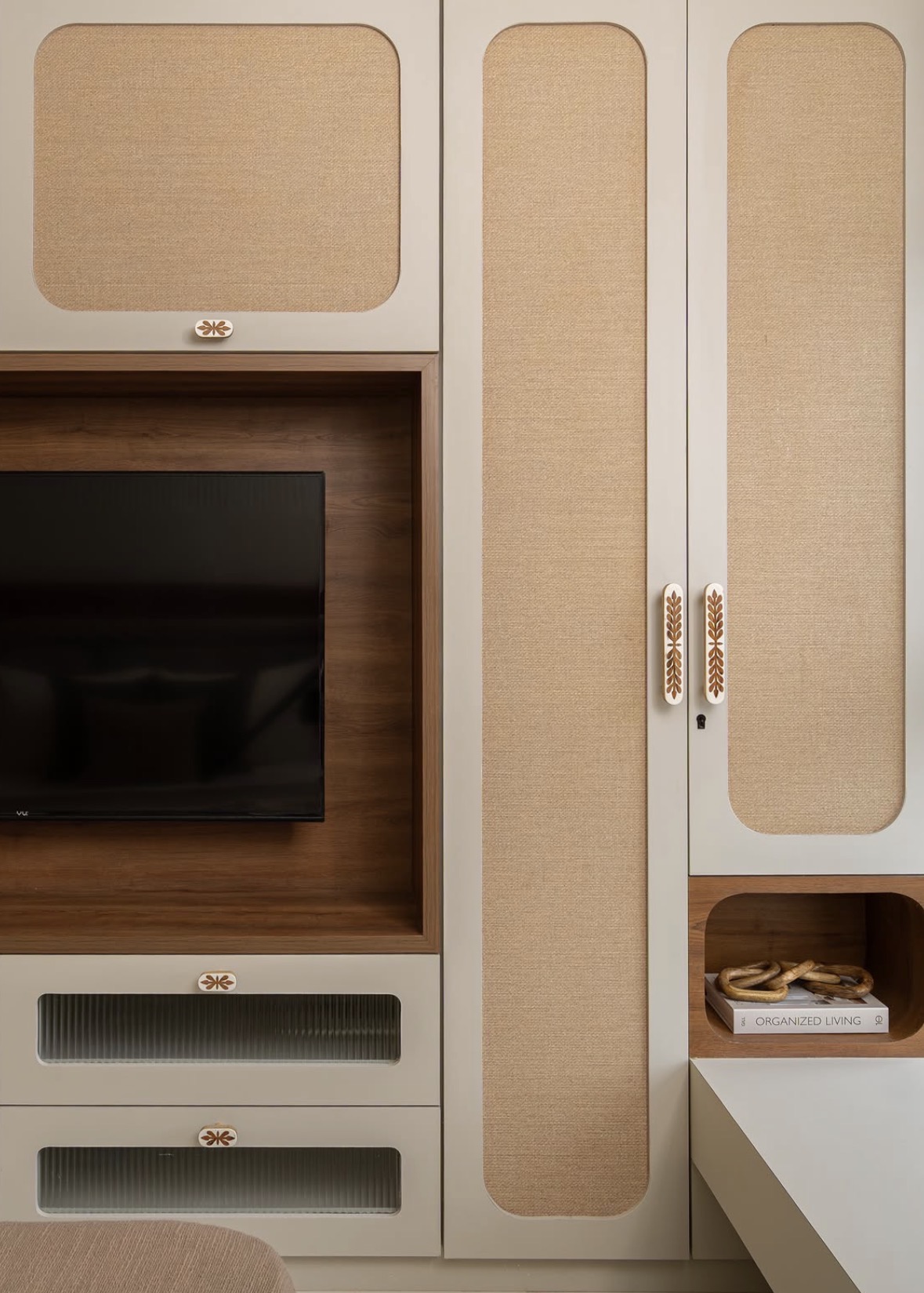 Cream wardrobe with rounded woven panels and inlaid handles beside a timber-framed television