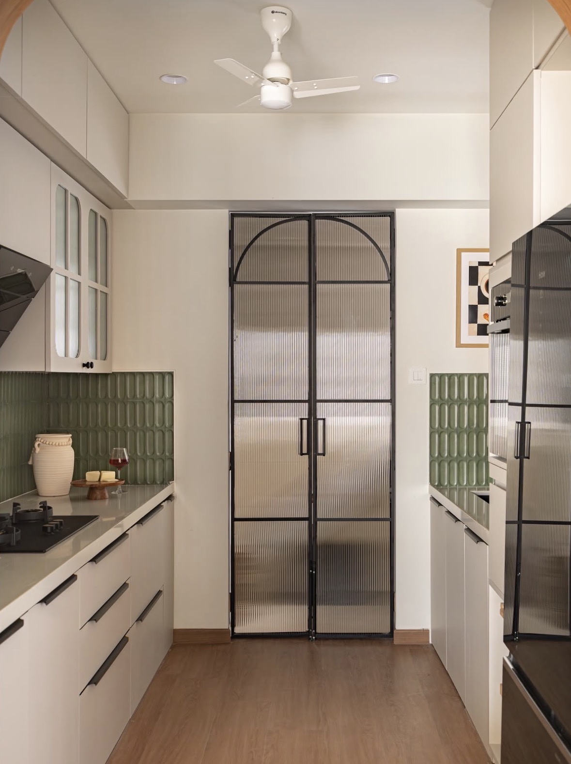 Narrow kitchen with a pair of arched black-framed reeded-glass doors at the end