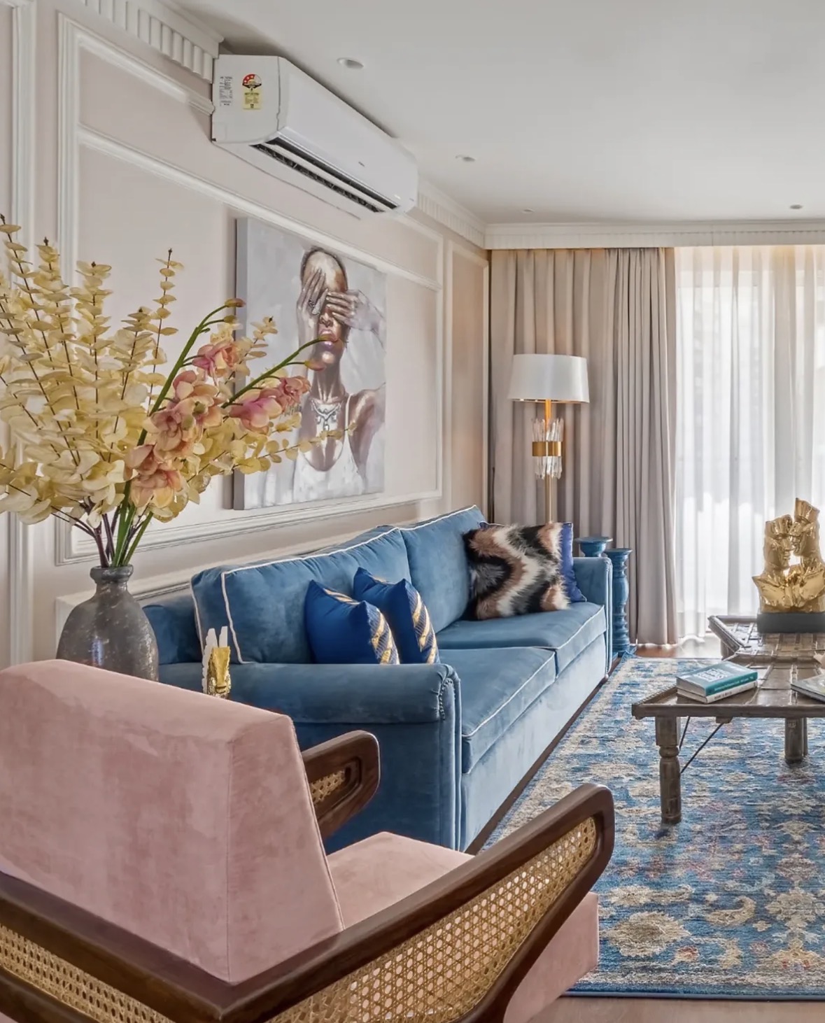 Cerulean sofa below a painted portrait on blush panelling, with a crystal floor lamp and a blush armchair