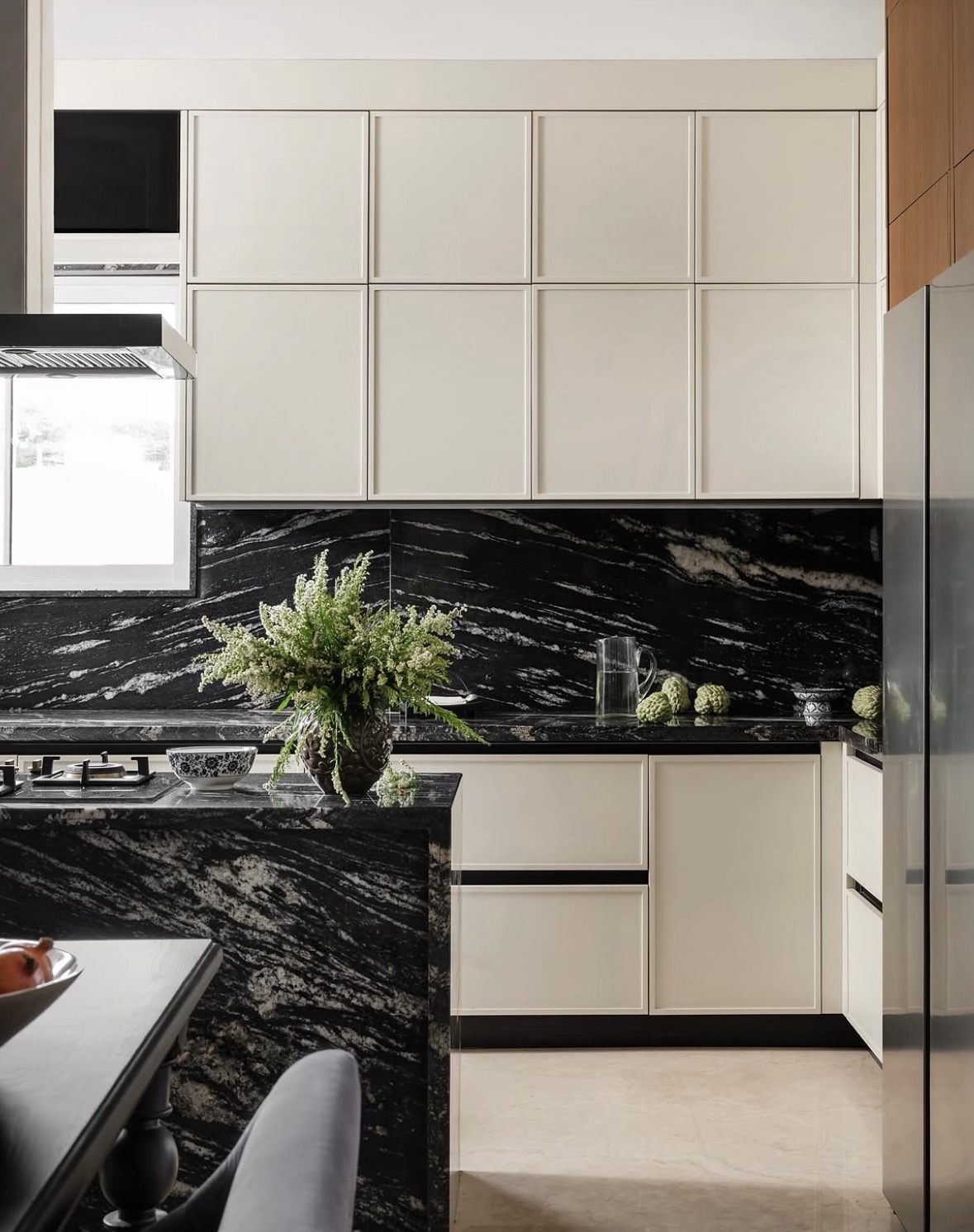 Kitchen with cream framed cabinets and a black granite backsplash and island