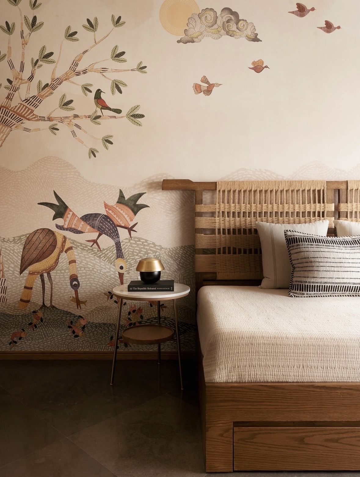Bed with a rope-woven headboard against a hand-painted mural of birds and a tree