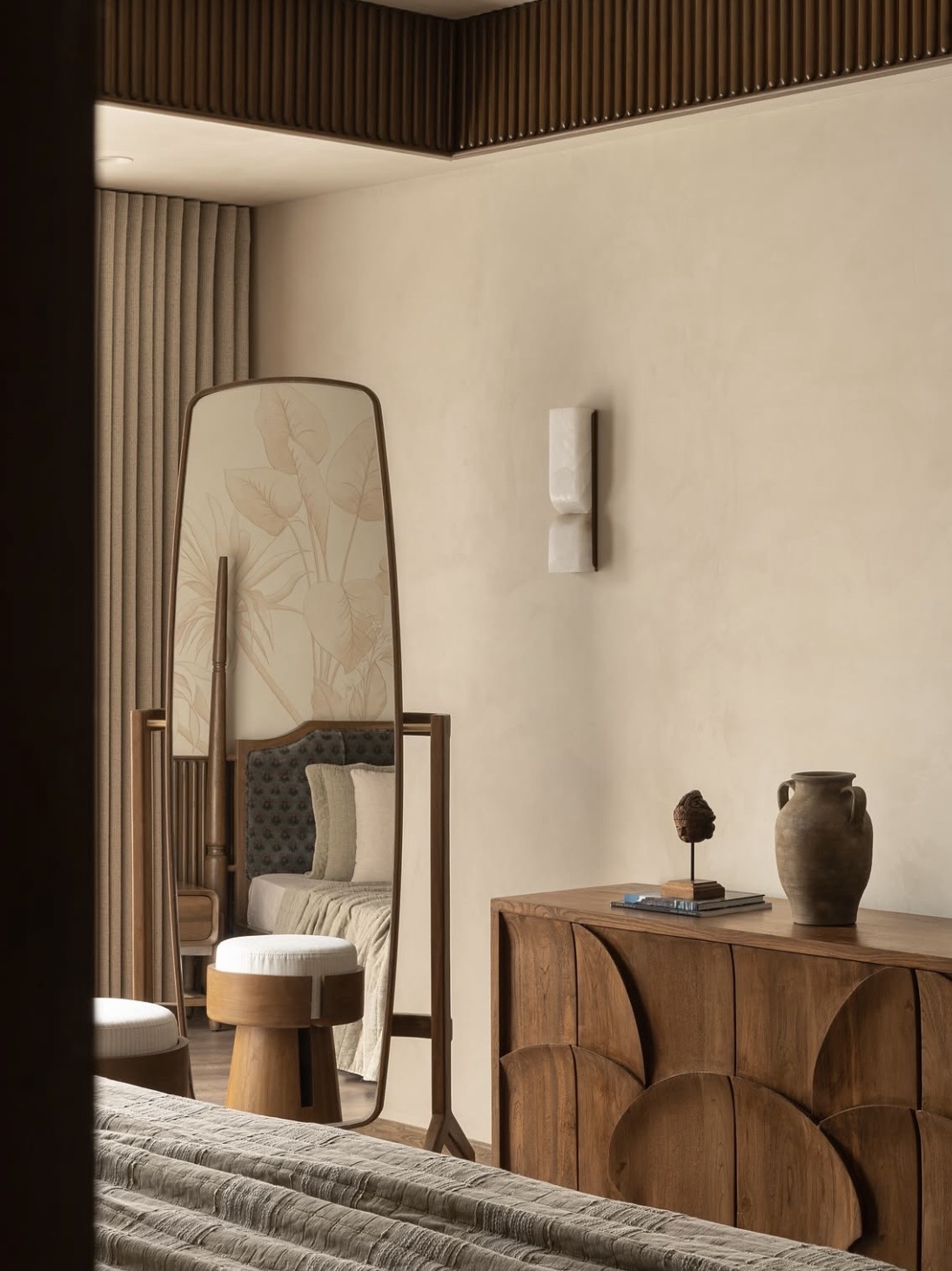 Standing mirror and a carved timber chest beneath a fluted timber ceiling edge