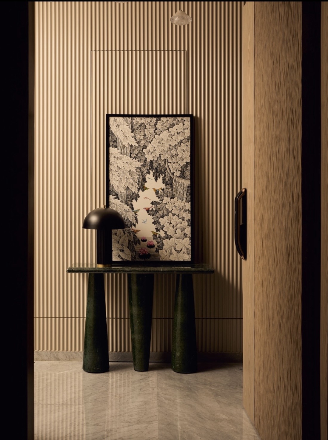 Green stone console with a black table lamp and a framed botanical print against fluted timber panelling