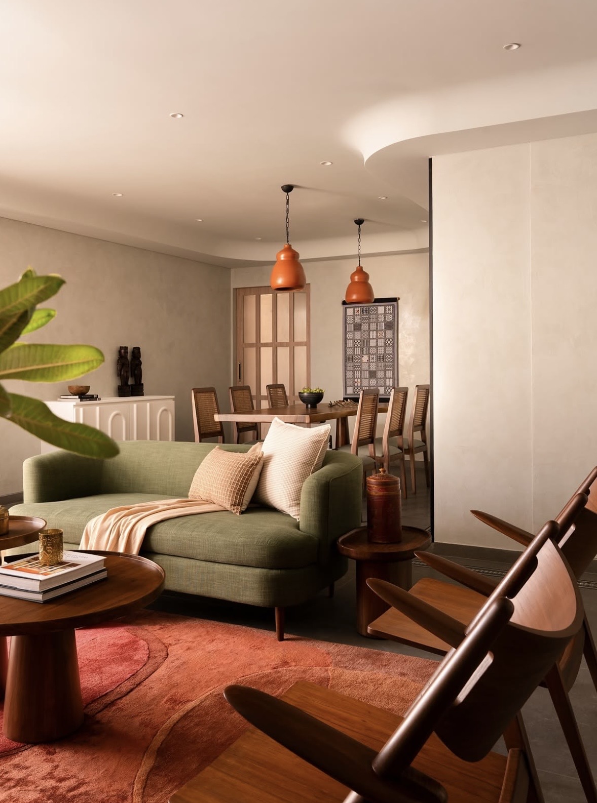 Green sofa and terracotta pendant lights, with the dining area beyond