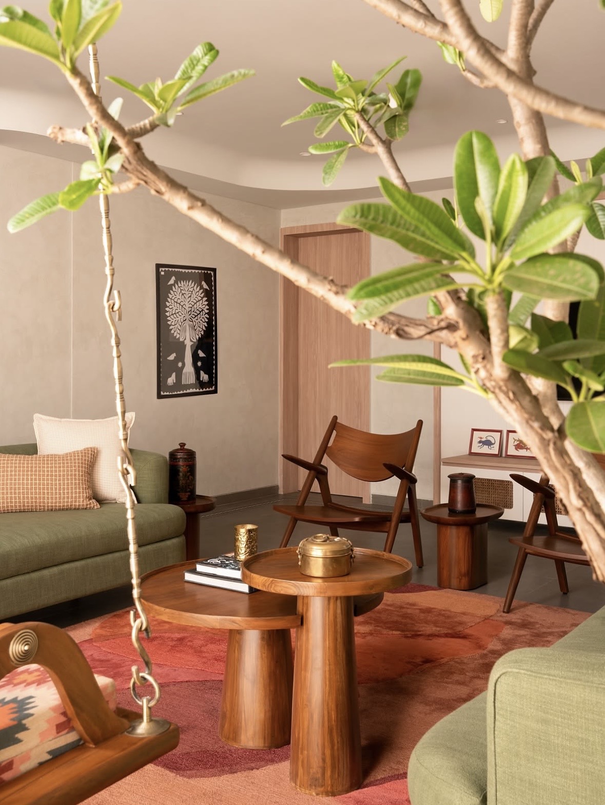 Round timber tables on a rust rug, framed by the branches of a flowering tree