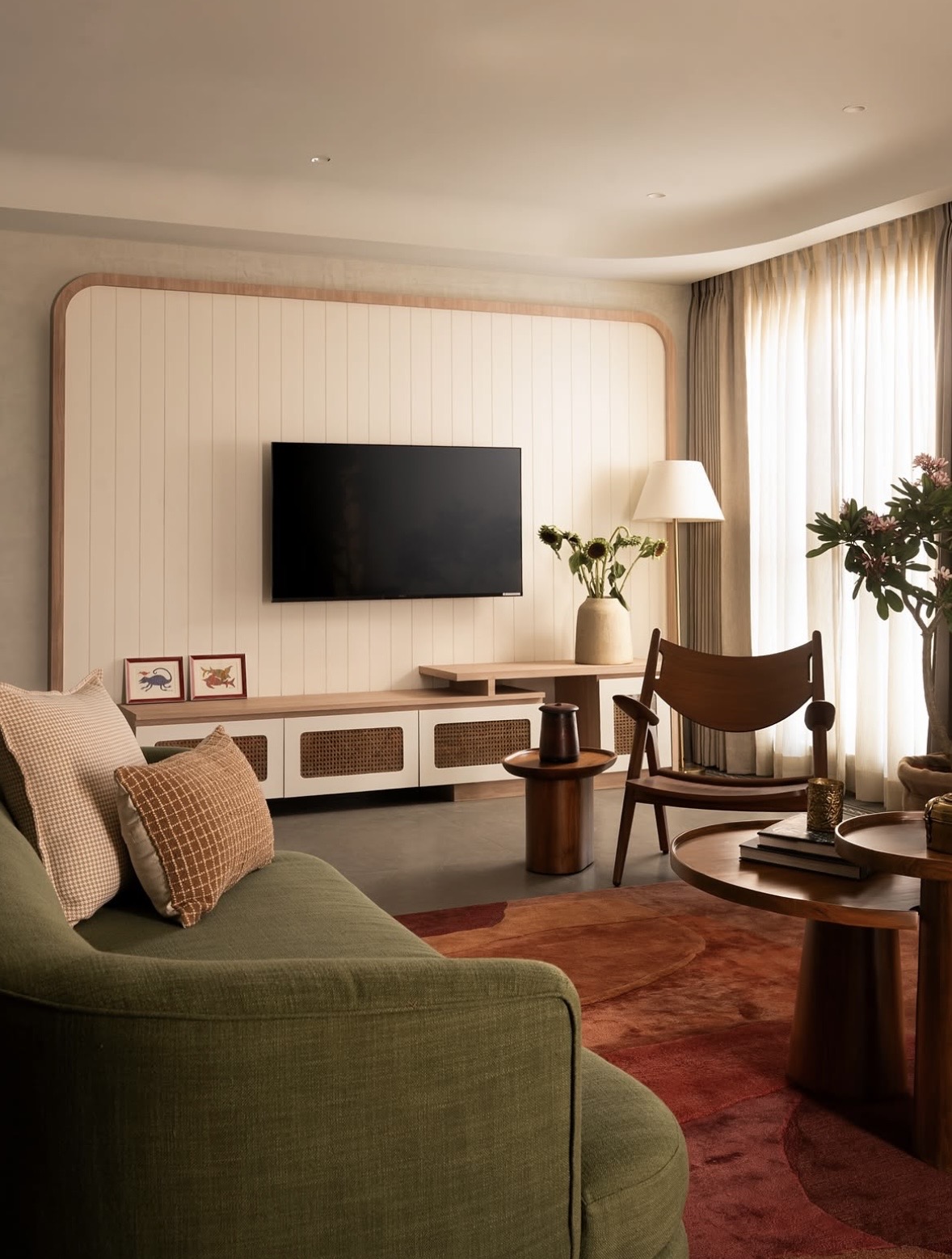 Living room with a timber-framed panelled television wall, a green sofa and a timber lounge chair
