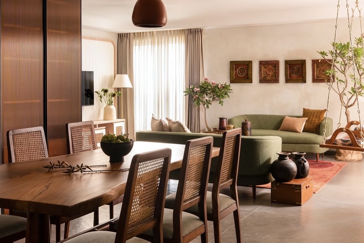 Dining table with cane-backed chairs, opening onto a living area with green sofas and a swing
