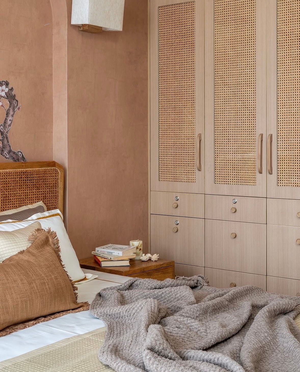 Wardrobe with woven cane doors and wooden handles beside a cane headboard