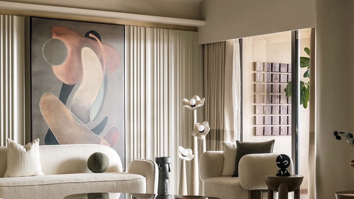 Living room with a large abstract painting above a cream bouclé sofa, a stone-topped table and a sculptural floor lamp