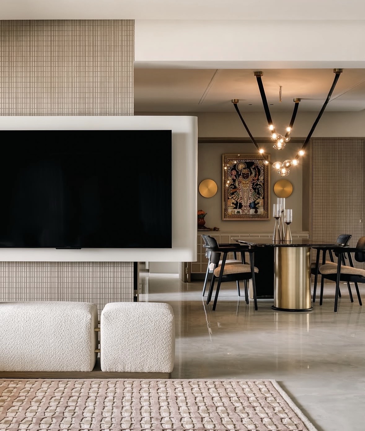 Wall-mounted television in a white frame, with the dining area and glass-globe lighting beyond