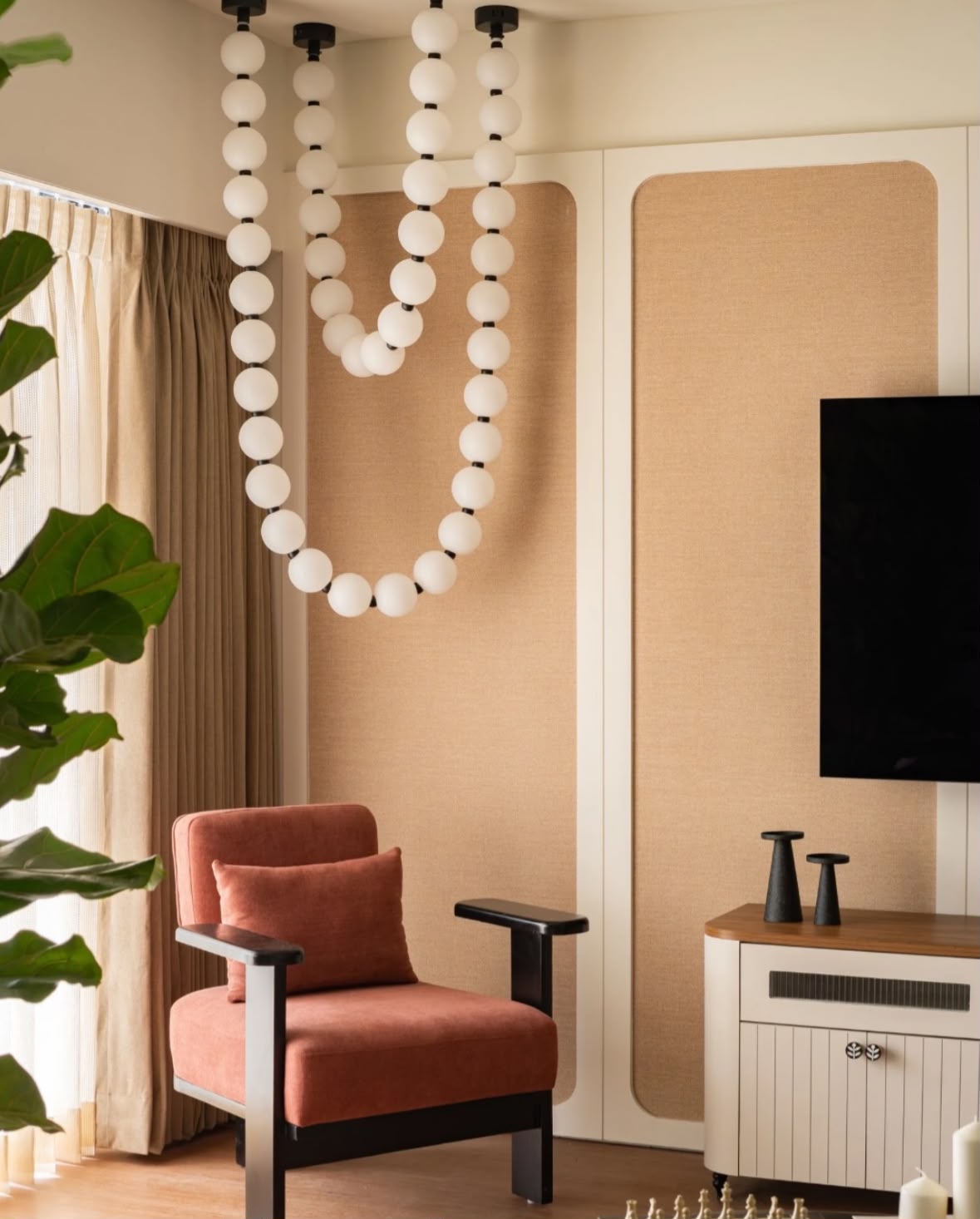 Strings of white beads hanging beside a rust armchair and a cane-panelled wall