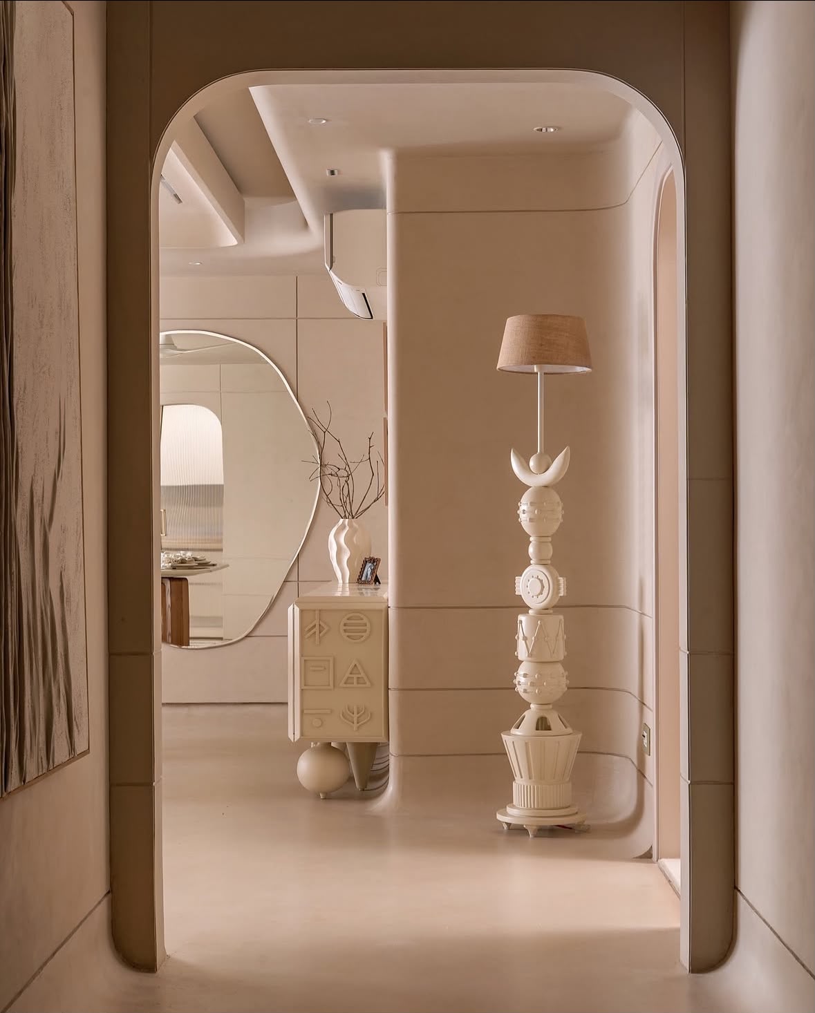 Arched passage with a sculptural white floor lamp and a curved mirror