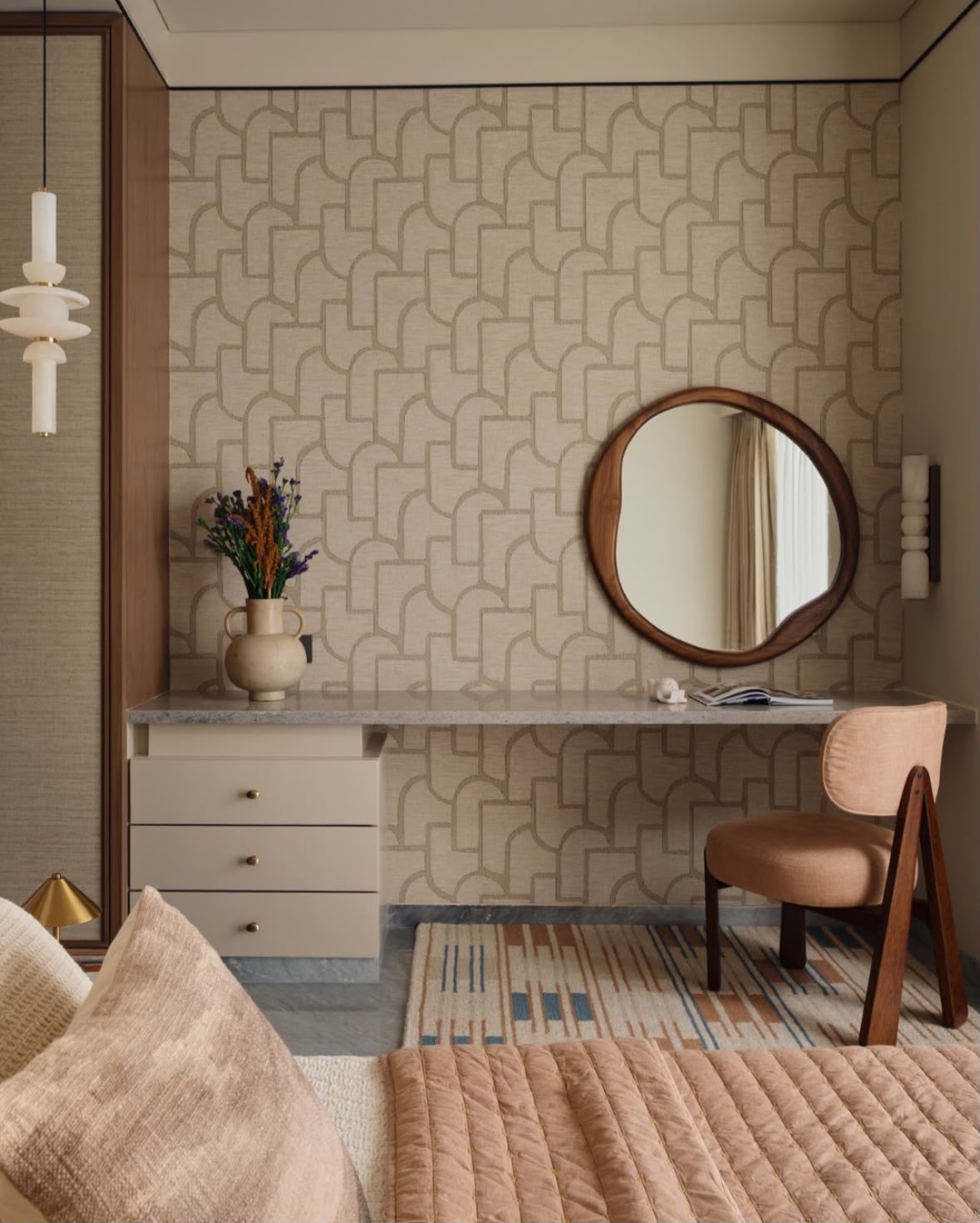 Dressing table with a round walnut mirror, a geometric wallpaper and a blush chair