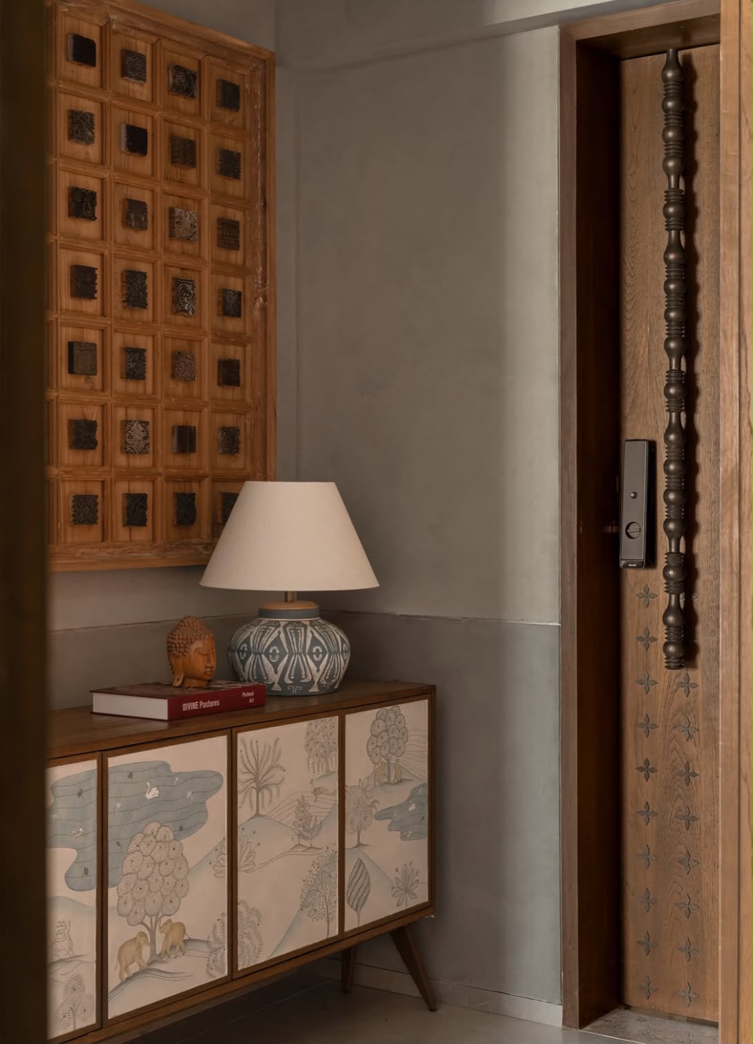 Carved timber panel above a painted cabinet beside a tall carved door