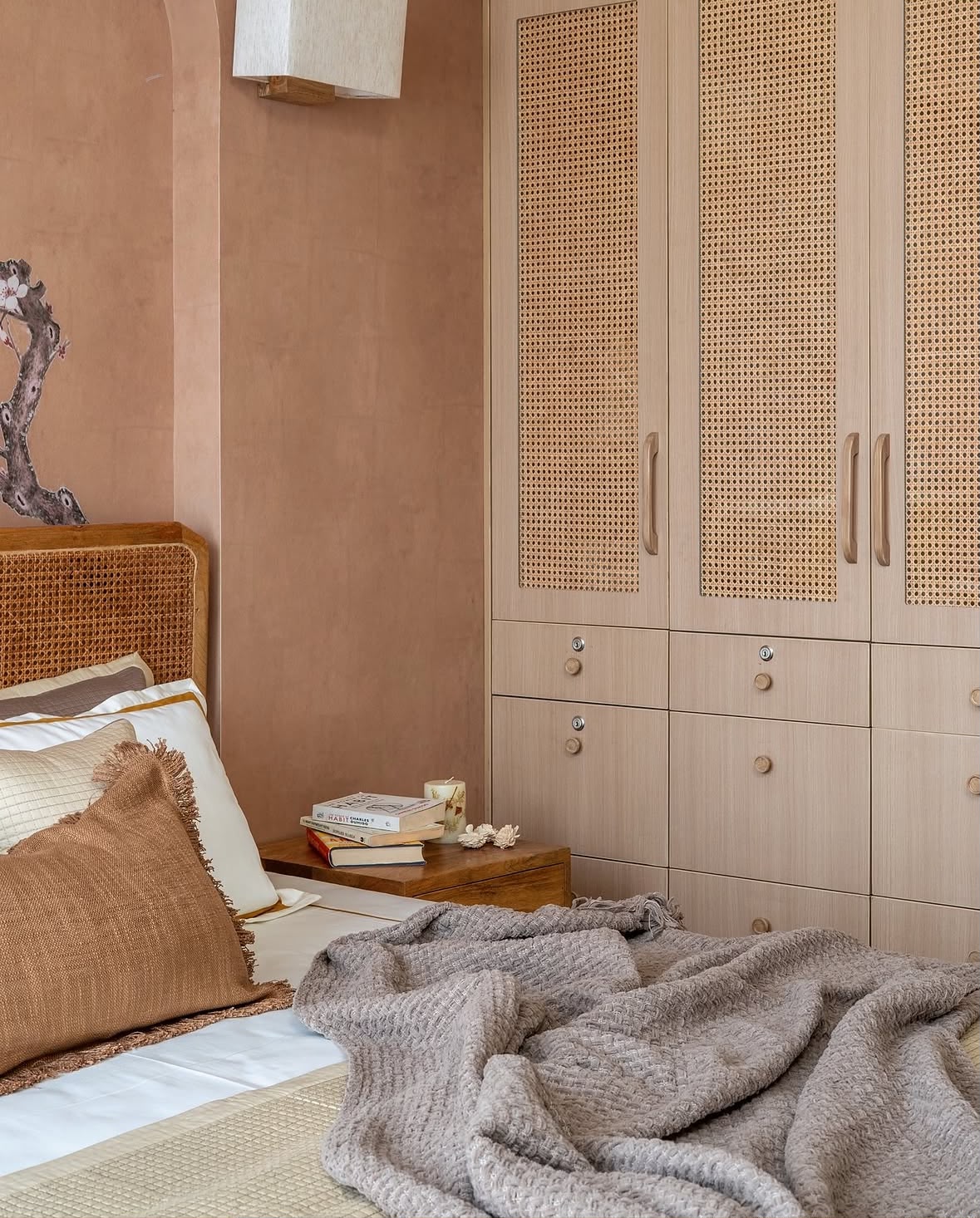 Bed beside a wardrobe with cane-panelled doors and fitted drawers