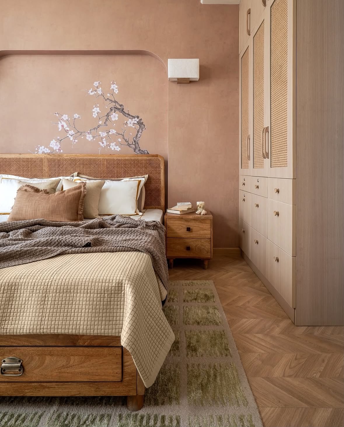 Bedroom with a cane headboard, a blush plaster wall and a painted blossom branch