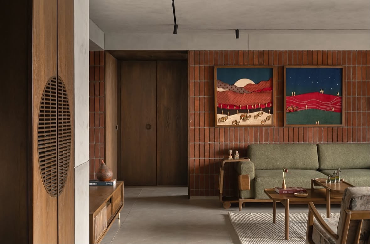 Living room with a green sofa against a brick wall and two framed paintings