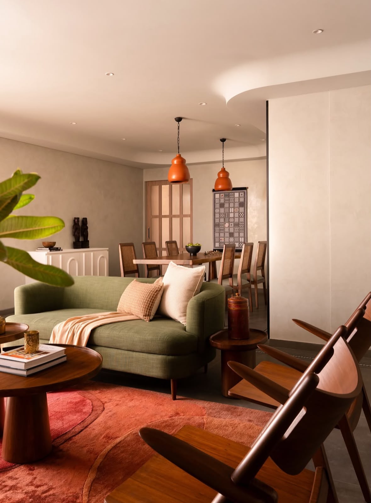 Living room with a green sofa, copper pendant lights and a dining area beyond
